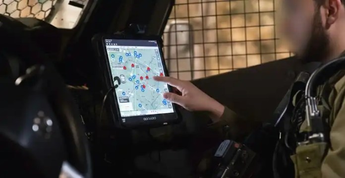 Soldado de las FDI utilizando el sistema ZAYAD en una tableta táctica con mapas digitales y marcadores de fuerzas aliadas y enemigas.